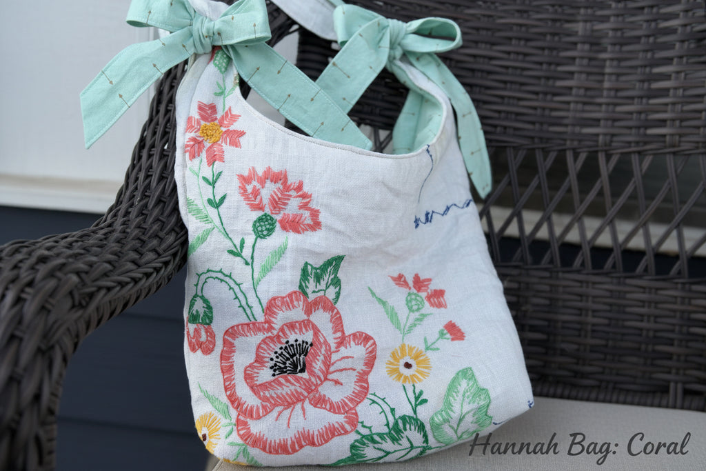 Floral embroidered bag with a green ribbon on a woven surface